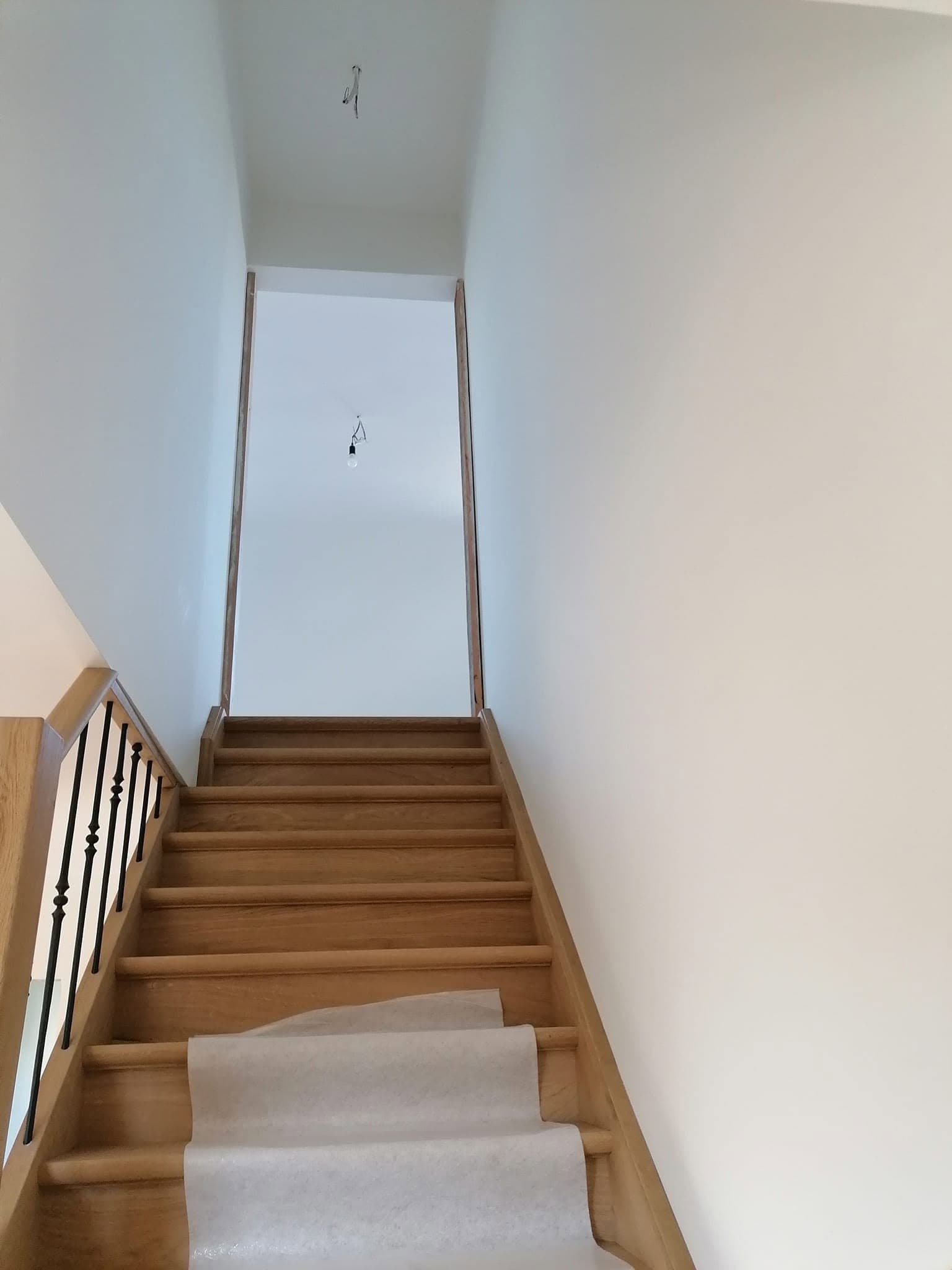 Houten trap met wit geschilderde wanden en trapwang